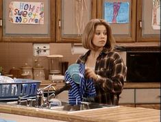 the young woman is pouring water into her kitchen sink while holding a blue object in her hand