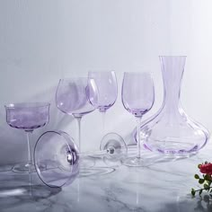 several wine glasses are lined up on a marble counter top with a rose in the foreground