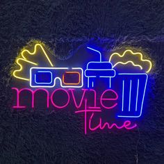 a neon sign that says movie time with glasses and a drink in front of it