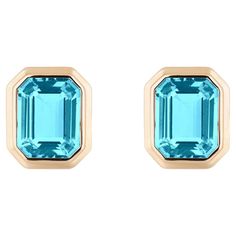 These Blue Topaz Emerald Cut Bezel Set Stud Earrings in 18K Yellow Gold from the 'Manhattan' Collection are an exquisite pair of earrings that exude elegance and sophistication. These earrings feature vibrant blue topaz gemstones with a captivating emerald-cut shape, carefully set in a luxurious 18K yellow gold bezel setting. The design is inspired by the sleek and modern aesthetics of Manhattan, making them a perfect choice for adding a touch of urban chic to any outfit. These stud earrings are Gem Earrings, Timeless Accessories, Vibrant Blue, Urban Chic, Topaz Gemstone, Classic Beauty, Modern Aesthetics, Bezel Setting, Emerald Cut