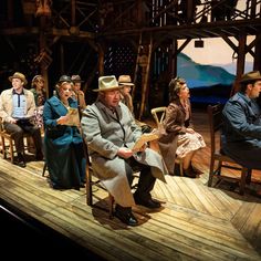 a group of people sitting on top of a wooden stage