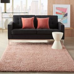 a living room with a black couch and pink pillows