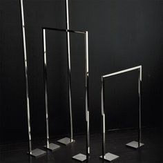 three metal poles are standing in front of a black wall and one has a white square on it