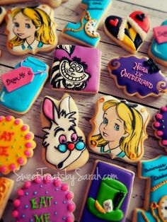 some decorated cookies are on a wooden table with the words alice and wonderland written on them