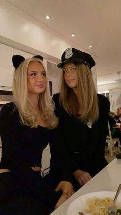 two women sitting at a table in front of a plate of food with cats ears on it