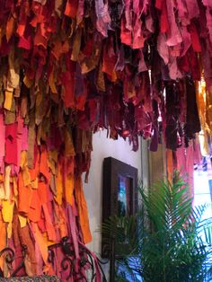 colorful streamers hang from the ceiling in an indoor area with potted plant and mirror