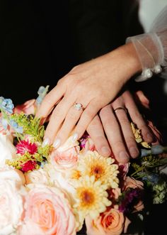 two hands touching each other over a bouquet of flowers