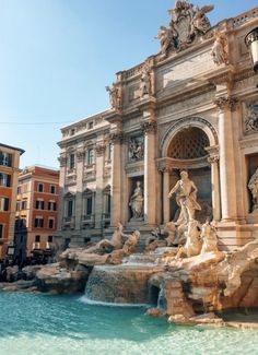 a fountain in front of a building with statues on the sides and water running down it