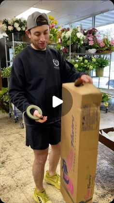 a man is opening a box with a pair of scissors in his hand while standing next to it