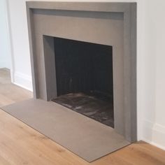 an empty fireplace in a white room with wood floors