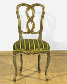 an antique chair with gold paint and green striped upholstered seat, sitting on a hard wood floor