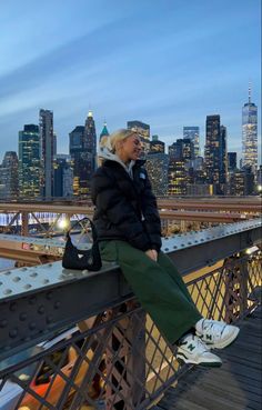 an older woman sitting on top of a bridge in front of a cityscape