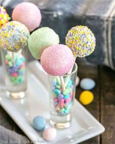 three small glass vases filled with candy and sprinkles on a tray