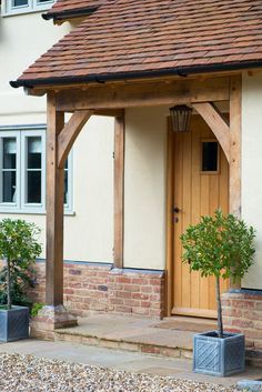 a small house with a tree in the front yard and potted plants on the side