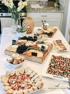 an assortment of appetizers on a table in a kitchen with flowers and potted plants