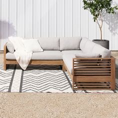 a white couch sitting on top of a rug next to a tree