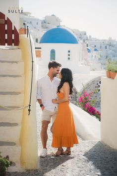 a man and woman standing next to each other in front of a blue domed building