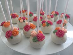 cake pops decorated with pink and orange flowers on a white platter, ready to be eaten