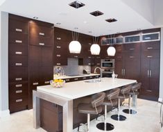 a large kitchen with an island in the middle and bar stools at the end