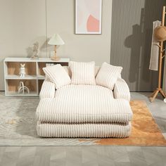 a white couch sitting on top of a rug next to a wooden table and lamp