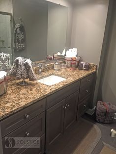 a bathroom with granite counter tops and gray cabinets