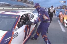 a man leaning out the window of a race car with other cars in the background