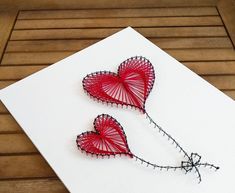 two red heart shaped pins sitting on top of a piece of paper