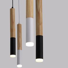 three wooden lights hanging from the ceiling with black, white and light wood tubes attached to them