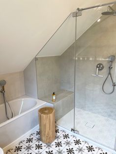 a bathroom with a walk in shower next to a white bathtub and wooden stool