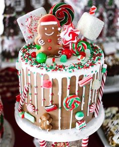 a decorated christmas cake with gingerbreads, candy and marshmallows on top