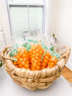 a basket filled with lots of oranges on top of a white table next to a window