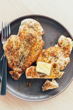 two pieces of chicken on a plate with butter