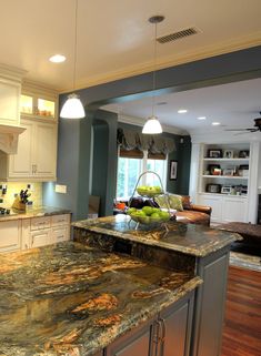 a large kitchen with marble counter tops and white cabinets