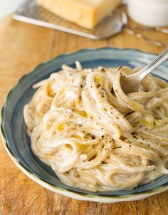 a plate of pasta with parmesan cheese on the side and a fork in it