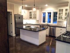 an empty kitchen with white cabinets and black counter tops is seen in this image from the doorway to the living room