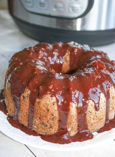 a bundt cake covered in chocolate sauce on a plate next to an instant pressure cooker