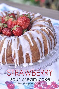 a bundt cake with icing and strawberries on top is sitting on a table