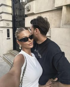 a man and woman taking a selfie in front of a building with their arms around each other