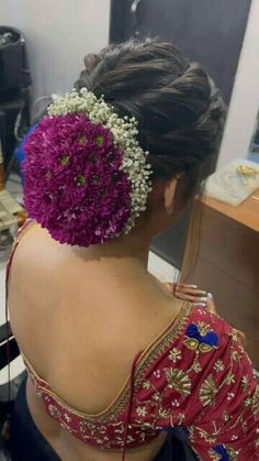 a woman sitting in front of a mirror wearing a red and blue blouse with flowers on it