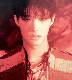 a young man is wearing a necklace and looking at the camera with an intense look on his face