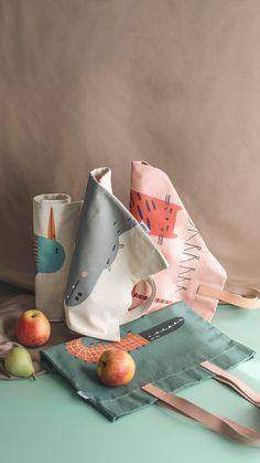 three different types of paper bags on a table with apples and spoons next to them