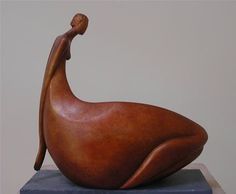 a wooden sculpture of a woman sitting on top of a blue stone block with a white wall in the background