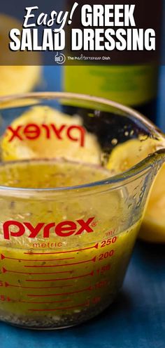 a measuring cup filled with yellow liquid next to sliced lemons on a blue surface