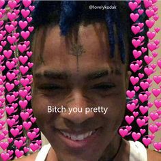 a man with blue dreadlocks smiles in front of pink hearts