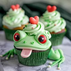 some cupcakes with green frosting and red eyes