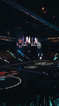 an empty basketball court with people watching from the sidelines and lights in the background