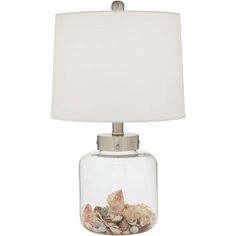 a glass lamp with shells in it and a white shade on the top of the lamp