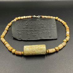 an ancient beaded necklace with gold beads and a small rectangular object on the side