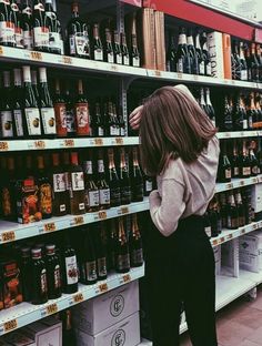 a woman standing in front of a shelf filled with beer bottles