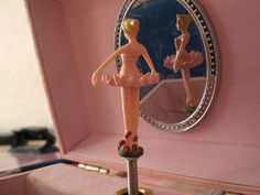 a pink jewelry box with a ballerina figure on it and a mirror in the background